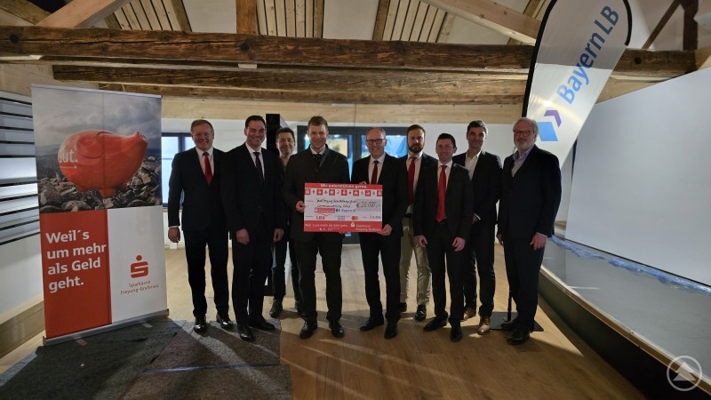 Die Sparkassenfinanzgruppe unterstützt die Bayerische Landesausstellung 2026 „Musik in Bayern“ mit 20.000 Euro – bei der Spendenübergabe v.li.: Dr. Mikko Klein (Vorstandsmitglied Sparkasse Freyung-Grafenau), Landrat Sebastian Gruber, Roland Pongratz (Musikalischer Leiter Volksmusikakademie Freyung), Dr. Olaf Heinrich (1. Bgm Freyung); Dietmar Attenbrunner (Vorstandsvorsitzender Sparkasse Freyung-Grafenau), Christopher Bonardi (Stv. Bezirksdirektor Versicherungskammer Bayern), Martin Kreuzer (Leiter Privatkunden Freyung, Sparkasse Freyung-Grafenau), Roland Schattenkirchner (Regionaldirektor LBS Süd) und Markus Kolbe (Regionaldirektor BayernLB). Mehrere Vertreter der Sparkassen-Finanzgruppe sowie regionale Verantwortliche stehen im TonYversum in Freyung zusammen und halten einen großen symbolischen Spendenscheck über 20000 Euro für die Bayerische Landesausstellung 2026 in den Händen.