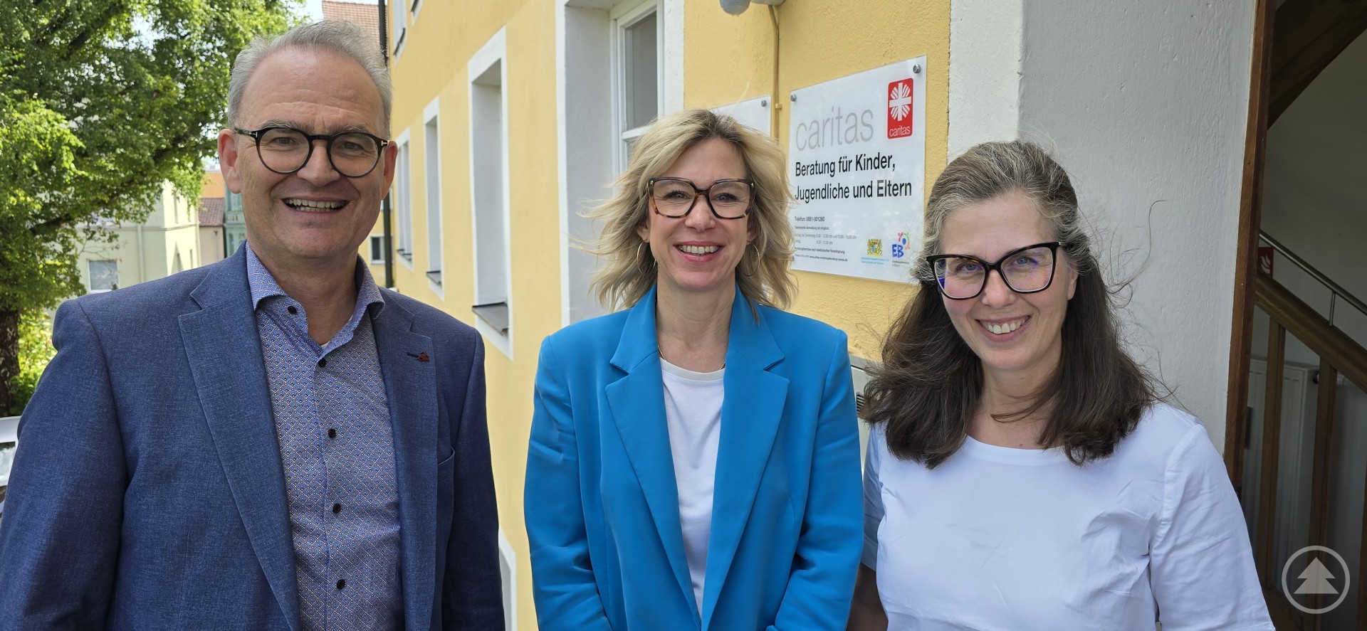 Caritasvorstand Stefan Seiderer und Fachbereichsleiterin Erika Paul (rechts) mit Stella Glück (Mitte), der neuen Leiterin der Beratungsstelle für Kinder, Jugendliche und Eltern. Drei Personen stehen vor einem gelben Gebäude der Caritas, darunter Stella Glück (Mitte), die neue Leiterin der Beratungsstelle.