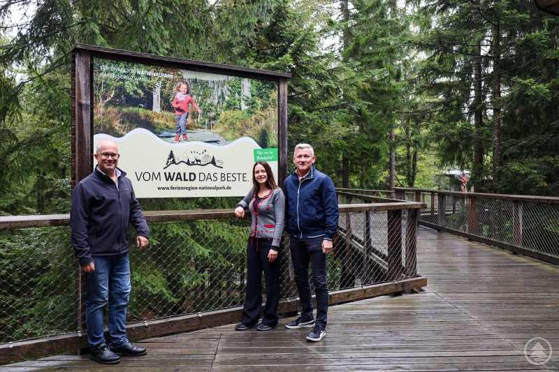 Robert Kürzinger, Geschäftsführer der Ferienregion Nationalpark Bayerischer Wald, Janine Hiksch, Standortleiterin am Baumwipfelpfad Bayerischer Wald und Alfons Schinabeck, Aufsichtsratsvorsitzender und erster Bürgermeister der FNBW-Mitgliedsgemeinde Neuschönau sind stolz auf die hervorragende Zusammenarbeit und präsentieren die neue Werbefläche.