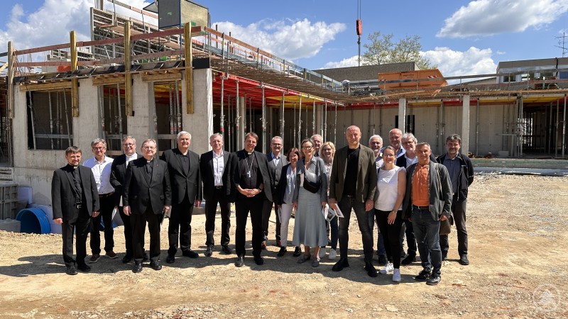 Gemeinsam für eine inklusive Zukunft: Vertreter der Caritas, des Bistums und der Architekten bei der Baustellenbesichtigung in Passau Gruppenfoto vor dem Rohbau mit Bischof Dr. Oster und weiteren Projektbeteiligten