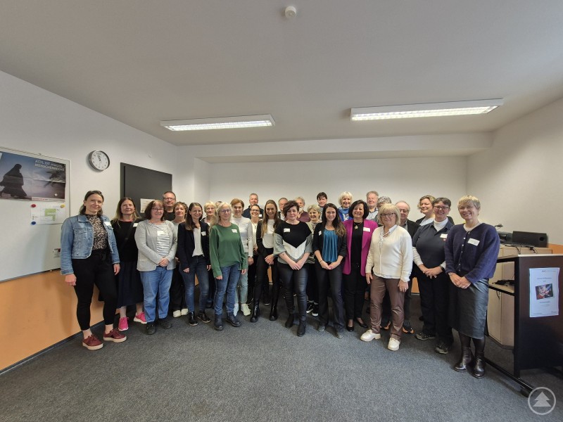 Freuten sich über die rege Teilnahme und die tatkräftige Atmosphäre beim Treffen der vhs-Dozentinnen und -Dozenten: stellvertretende Landrätin Helga Weinberger (vorne links) und vhs-Leiterin Karina Fisch (vorne rechts) zusammen mit ihrem Team. Eine große Gruppe von Dozentinnen, Dozenten und Mitarbeitenden der vhs Freyung-Grafenau steht gemeinsam in einem Schulungsraum. Alle lächeln in die Kamera, im Hintergrund sind Tafel und Leinwand zu sehen.