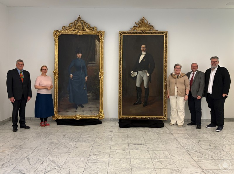 Auf dem Bild v.l.n.r.: Schatzmeister Förderverein Oberhausmuseum e.V. Franz Kreilinger, Museumsleiterin Dr. Stefanie Buchhold, 2. Vorsitzende Förderverein Oberhausmuseum e.V. Stephanie Holly, 1. Vorsitzender Förderverein Oberhausmuseum e.V. Mario Puhane, Bürgermeister Andreas Rother Sechs Personen stehen in einer hellen Ausstellungshalle des Oberhausmuseums Passau neben zwei imposanten, vergoldeten Porträtgemälden. Die Gemälde zeigen eine Frau im Reitkostüm und einen Mann im Reitdress, beide in üppig verzierten goldenen Rahmen. Die Gemälde sind nahezu drei Meter hoch.