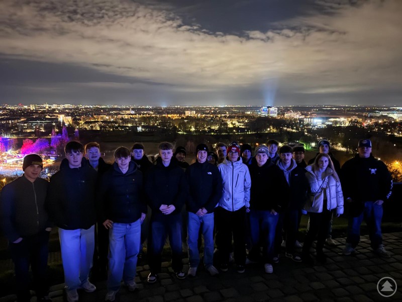 Am Abend verschafften sich die Grafenauer Jugendlichen mit ihren Lehrkräften vom Olympiahügel aus einen Überblick über die Landeshauptstadt. Mehrere Jugendliche und Begleitpersonen stehen auf einer Anhöhe und blicken auf das nächtlich beleuchtete München mit zahlreichen Lichtern und Gebäuden im Hintergrund.