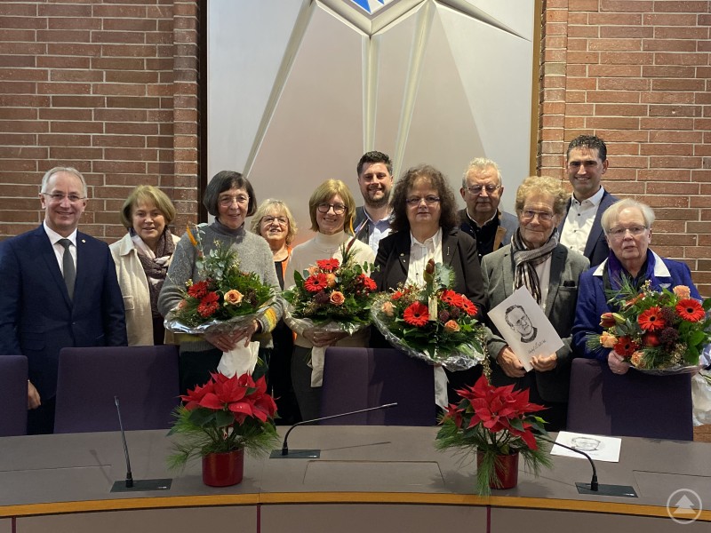 Die Preisträgerinnen und Preisträger Maria Birkeneder sowie Vertreterinnen und Vertreter des Arbeitskreises Heimatgeschichte Mitterfels e.V. bei der Verleihung der Josef-Schlicht-Medaille im Landratsamt Straubing-Bogen. Mehrere geehrte Personen stehen im Sitzungssaal des Landratsamtes Straubing-Bogen vor einer Holzvertäfelung. In der ersten Reihe halten die Ausgezeichneten Blumensträuße und Urkunden, dahinter stehen Vertreter aus Politik und Verwaltung. Alle Beteiligten posieren gemeinsam für ein Gruppenfoto.