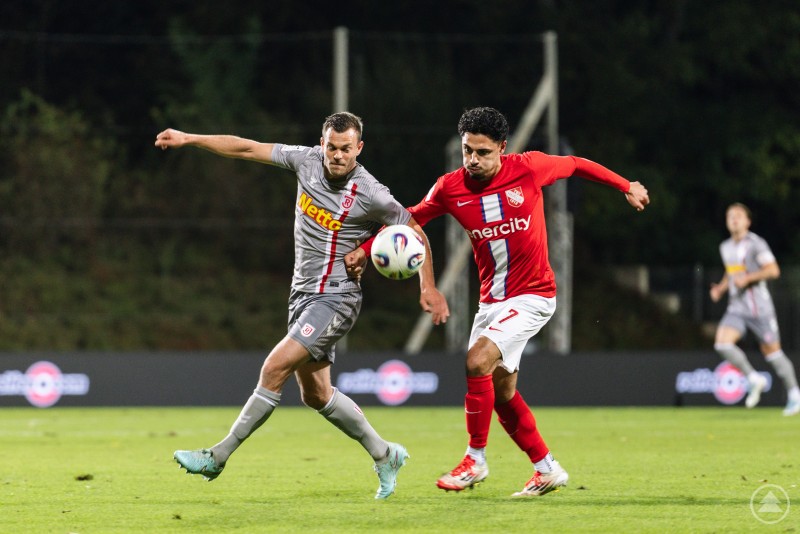 Ein Jahn-Spieler und ein Havelser sprinten nebeneinander dem Ball entgegen, beide strecken im Lauf das Bein aus.