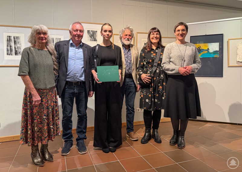Feierten eine gelungene und gut besuchte Ausstellungseröffnung (v. l.): Gabi Hanner, Alfons Neubauer, Giulia Timea Fioranti, Rudi Ranzinger, Eva Kühberger und Nationalparkleiterin Ursula Schuster. Sechs Personen stehen bei der Ausstellungseröffnung im Waldgeschichtlichen Museum in St. Oswald nebeneinander vor mehreren ausgestellten Kunstwerken. In der Mitte hält eine junge Pianistin eine grüne Mappe in den Händen, während die Gruppe für ein gemeinsames Erinnerungsfoto posiert.
