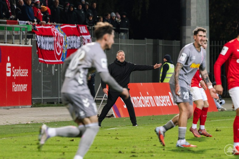 Cheftrainer Michael Wimmer dirigierte seine Mannschaft lautstark zum wichtigen Auswärtssieg in Hannover. Cheftrainer Michael Wimmer steht an der Seitenlinie und gibt lautstark Anweisungen, während seine Spieler auf dem Feld agieren.