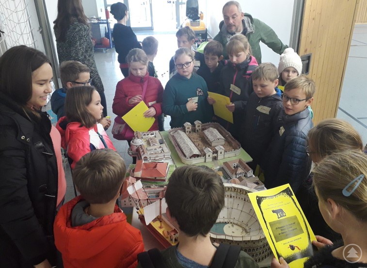 Eine der Teilnehmerinnen an P-Seminar, Anna-Lena Madl (links), erklärt den jungen Besuchern die verschiedenen Modelle antiker Bauwerke.