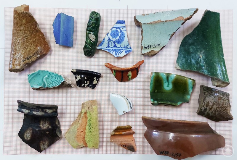 Verschiedene Scherbenfunde rund um das Schloss Wolfstein lassen auf die Besiedlungsgeschichte des Landkreises schließen. Eine Sammlung verschiedener Keramikscherben auf einem karierten Hintergrund, die Funde aus der Region um das Schloss Wolfstein darstellen.