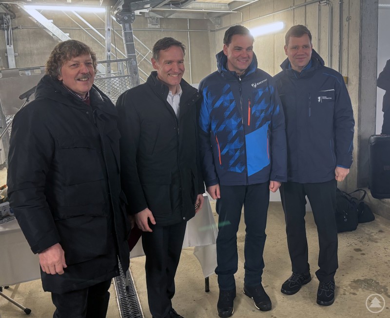 Vier Vertreter aus Politik und Region stehen nebeneinander in einer Liftstation und posieren f&uuml;r ein Gruppenfoto.