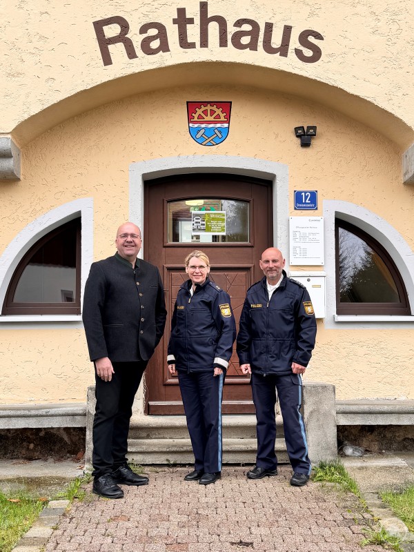 Zufrieden mit der Sicherheitslage sind Bürgermeister Roland Schraml, Polizeioberkommissarin Ingrid Grötzinger und Polizeihauptkommissar Georg Binder. Drei Personen, darunter zwei in Polizeiuniform, stehen vor dem Eingang des Rathauses der Gemeinde Haidmühle.