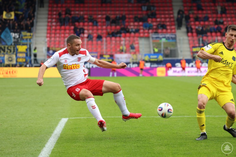 Ein Spieler des SSV Jahn Regensburg versucht am Spielfeldrand, den Ball vor einem Gegner zu erreichen.