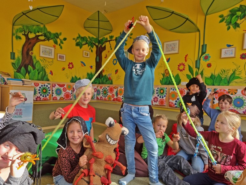 Beim Vorlesen des Buchs „Die wilden 14“ über die Urwaldkäfer der Region führte diese Gruppe gleich spontan ein kleines Theater auf. Eine Gruppe Grundschulkinder spielt mit bunten Figuren und stellt eine Szene aus einem Buch über Urwaldkäfer dar.