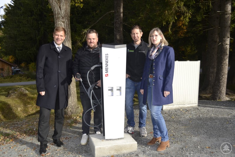 Olaf Heinrich, Heiner Kilger, Michael Pongratz Firma EGT und Stephanie Herzig (Betriebsleitung) Vier Personen stehen neben einer neuen öffentlichen E-Ladesäule auf dem Gelände des Freilichtmuseums Finsterau. Eine Person hält den Ladestecker, im Hintergrund sind Bäume und ein kleiner Wirtschaftsweg zu sehen.