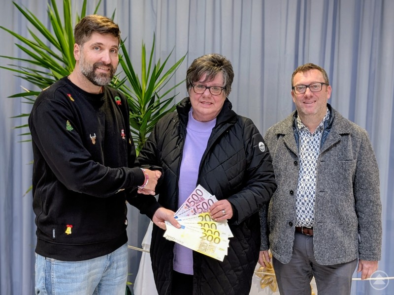 Schulleiter Ferdinand Klingelhöfer (von li.) überreichte im Namen der Realschule Grafenau den Vertretern der Spiegelauer Tafel „Bürger helfen Bürgern“ Waltraud Madl und 2. Bürgermeister Günther Nama einen Teil der Einnahmen aus dem sozialen Tag in Höhe von 1.776 Euro. Drei Personen stehen nebeneinander, eine Frau in der Mitte hält mehrere Geldscheine, während der Mann links ihr die Hand schüttelt.