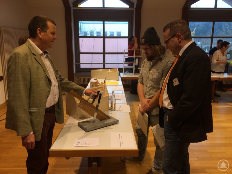 Lehrer Thomas A. Ziegler (links) von der Dietrich-Bonhoeffer-Schule in Schönberg stellt dem Jurorenteam Malte Trilling (Arbeitskreis SCHULEWIRTSCHAFT Freyung-Grafenau, rechts) und Uli Hansel (Ultima Design, Mitte) die Werkstücke seiner Schüler vor.