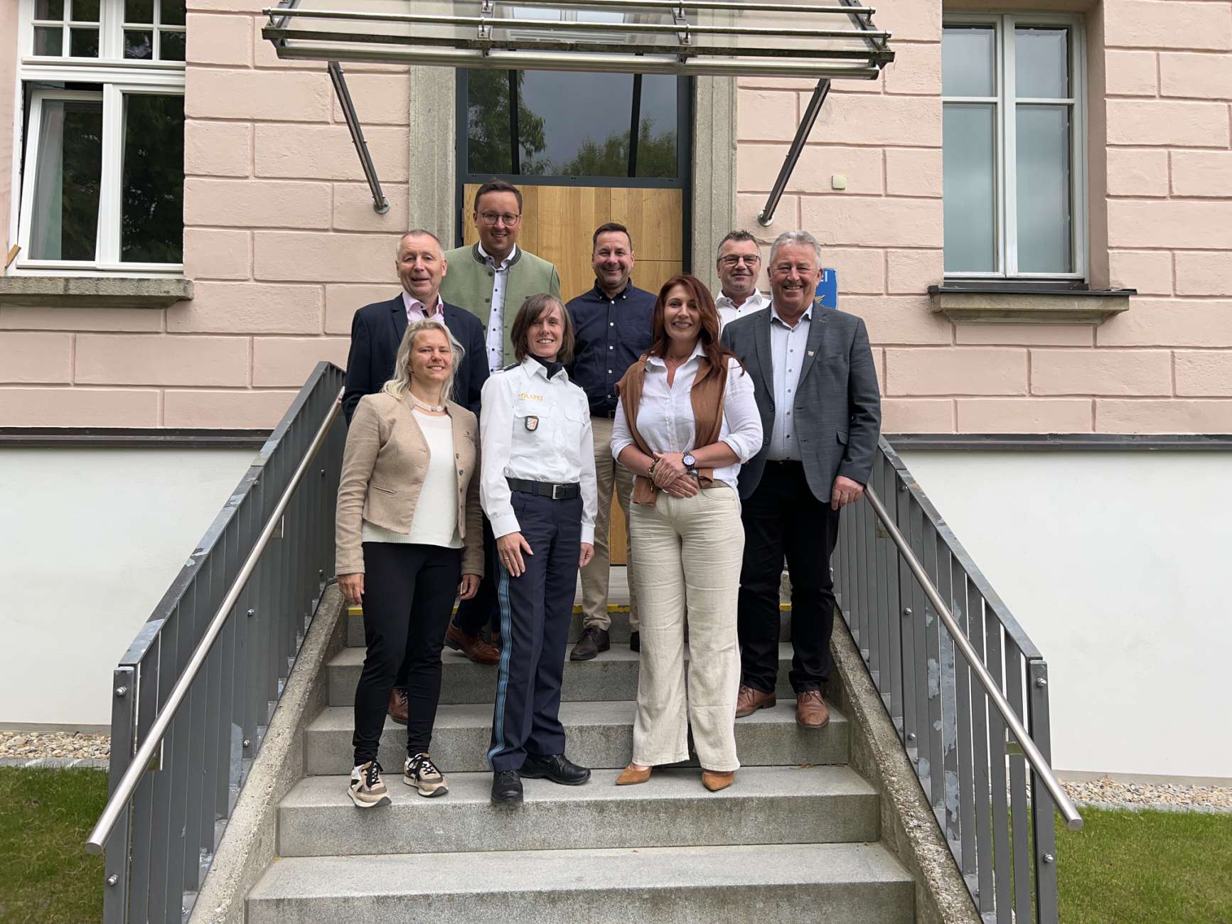 Teilnehmer des Sicherheitsgesprächs zwischen der Polizeiinspektion Regen und den Bürgermeistern der Stadt Regen und der umliegenden Gemeinden. Eine Gruppe von acht Personen, darunter Polizeibeamte und Bürgermeister, steht auf einer Treppe vor einem Verwaltungsgebäude. Sie blicken freundlich in die Kamera.
