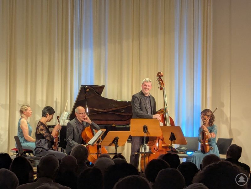 Der gebürtige Deggendorfer Thomas Hille (stehend) richtete herzliche Worte an die Anwesenden. Musiker des Klavierquintetts lächeln ins Publikum