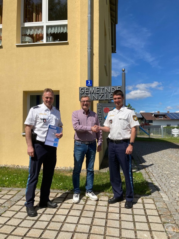 EPHK Thomas Kern und PHK Franz Weinzierl von der Polizeiinspektion Grafenau beim Sicherheitsgespräch mit Bürgermeister Josef Kern vor der Gemeindekanzlei Innernzell. Drei Männer stehen vor einem gelben Gemeindegebäude in Innernzell, zwei in Polizeiuniform und einer in Freizeitkleidung, geben sich die Hand bei sonnigem Wetter.
