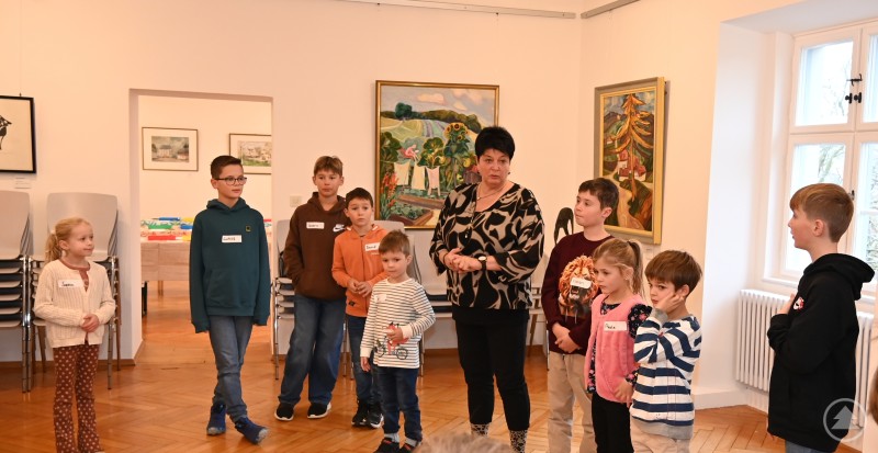 Spannende Einblicke und Aktionen hatte Museumspädagogin Ramona Kesten bei der Führung durch die Galerie im Schloss Wolfstein parat. Eine Gruppe von Kindern steht mit einer Betreuerin in einem Ausstellungsraum der Galerie Wolfstein, umgeben von Kunstwerken an den Wänden.
