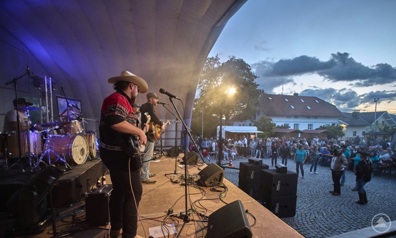 Blick von der Bühne auf die Band und das Publikum, das sich am Marktplatz in Bodenmais zum Festival versammelt hat. 