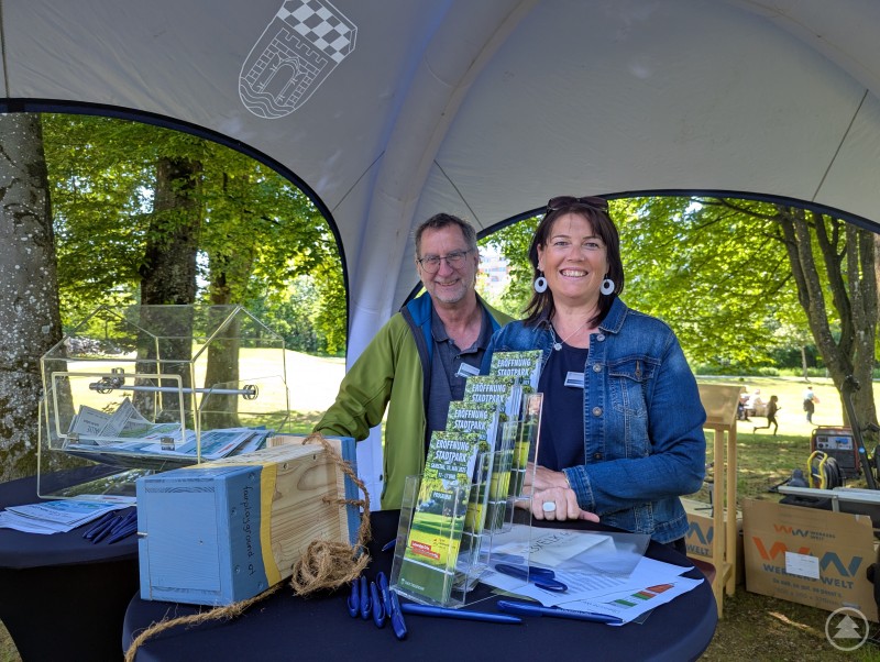 Blauer Infopavillon mit zwei freundlichen Mitarbeitenden