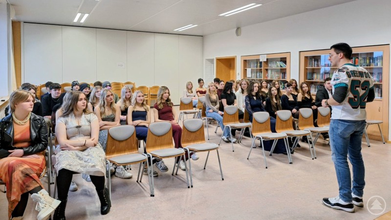 Richter Martin Metzler vom Amtsgericht Passau klärte die Grafenauer Realschüler über die Gefahren sowie rechtlichen Auswirkungen von Alkohol und Drogen im Straßenverkehr auf. Ein Referent spricht vor Schülerinnen und Schülern der Realschule Grafenau, die in festlicher Kleidung auf Stühlen sitzen und aufmerksam zuhören.
