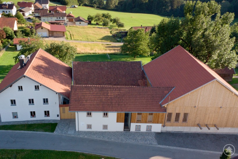 uftaufnahme des sanierten Vierseithofs in Liebersberg mit angrenzenden Gebäuden und Grünflächen.