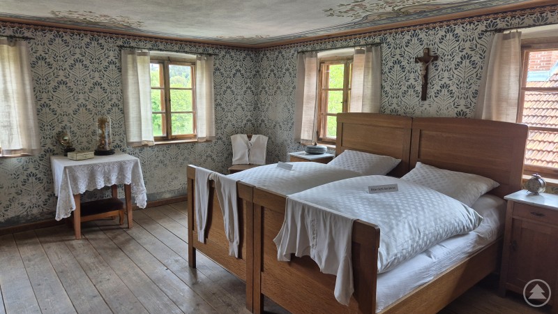 Die Schlafkammer mit schönem Dekor Schlafkammer mit Dekor an den Wänden, großes Holzehebett. Über dem Bett ein Kreuz