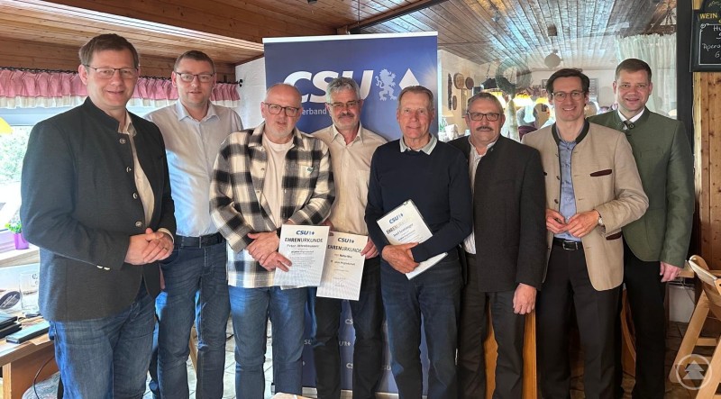 Mandatsträger und Ehrengäste gratulieren den geehrten Mitgliedschaftsjubilaren: v. li. n. re. MdB Thomas Erndl, 3. Bürgermeister Christoph Endl, Peter Attenbrunner, Walter Mini, Josef Leutzinger, Ortsvorsitzender Otto Christoph, MdL Dr. Stefan Ebner und Bürgermeister Dr. Olaf Heinrich. Mehrere Männer stehen in einem Gastraum vor einem CSU-Banner und halten Urkunden in der Hand. Die Gruppe lächelt in die Kamera.