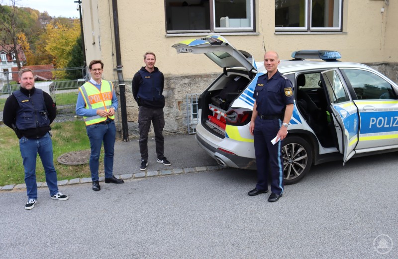 Zusammen mit den Fahndern Dominik Resch (links) und Klaus Kühbeck (2.v.l.) zeigen Inspektionsleiter der Polizeiinspektion Zwiesel Erster Hauptkommissar Till Hauptmann (r.) ihrem Gast, dem Landtagsabgeordneten Stefan Ebner, die vielen Materialien, die in einem Einsatzfahrzeug der Polizei mitgeführt werden müssen. Polizei Zwiesel 01.JPG