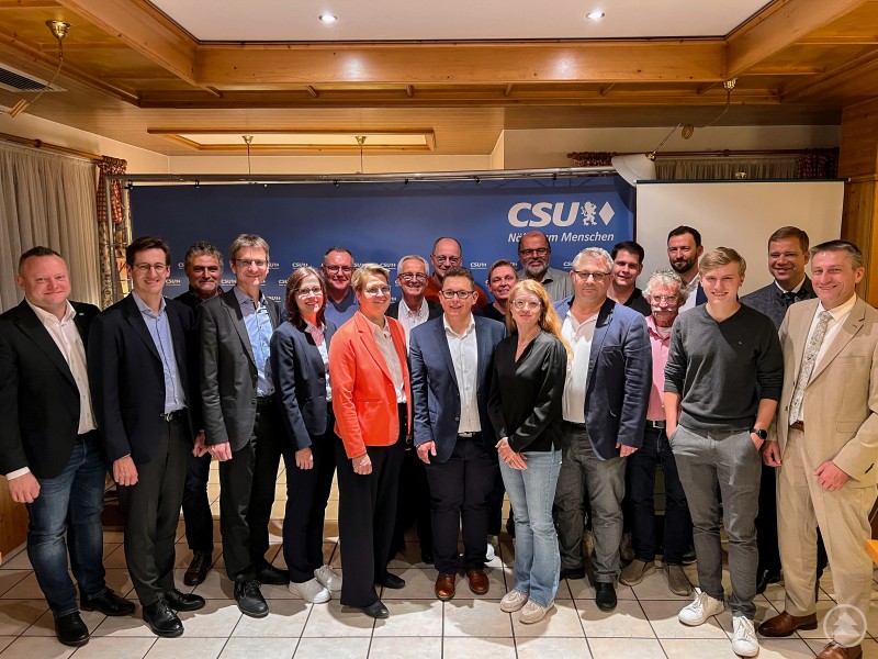 Stadtrat und MU-Kreisvorsitzender Stefan Behringer, MdL Dr. Stefan Ebner, Charly Bumann, Erster Bürgermeister von Spiegelau und Stv. Kreisvorsitzender der CSU Karlheinz Roth, Stellvertretende Kreisvorsitzende der Jungen Union Freyung Grafenau Laura Dick, Jürgen Schallmair, FU-Kreisvorsitzende Christine Engel, 2. Bürgermeister Max Riedl, Stadtrat Karl Mayer, Bürgermeisterkandidat Jonas Höcker, Tabea Fredl, FU-Ortsvorsitzende Eva Endl, Stadtrat Konrad Bauer, CSU-Ortsvorsitzender Florian Kilger, JU-Ortsvorsitzender Sebastian Schrank, 3. Bürgermeister Wolfgang Kunz, Dr. Stefan Blöchl, Christoph Danzer, Bezirkstagspräsident und Erster Bürgermeister von Freyung Dr. Olaf Heinrich, Stellvertretender Kreisvorsitzender der CSU Tassilo Pichlmeier Eine größere Gruppe von Männern und Frauen steht in einem Veranstaltungsraum vor einer blauen CSU-Hinterwand. Alle blicken in die Kamera und lächeln. Die Personen stehen dicht beieinander, teils in Business- oder Freizeitkleidung.