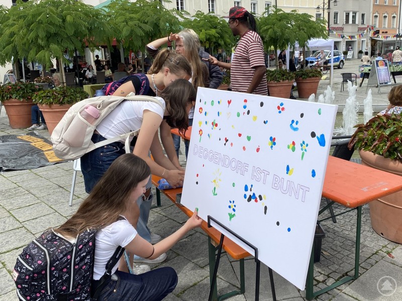 Mehrere Schülerinnen kleben bunte Punkte auf eine große Tafel mit der Aufschrift „Demokratie ist bunt“ bei einer Aktion auf dem Deggendorfer Stadtplatz. Mehrere Schülerinnen kleben bunte Punkte auf eine große Tafel mit der Aufschrift „Demokratie ist bunt“ bei einer Aktion auf dem Deggendorfer Stadtplatz.