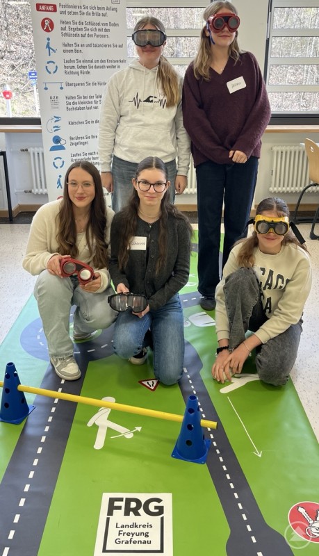 Gruppe von Schülerinnen mit Rauschbrillen auf einem markierten Parcours
