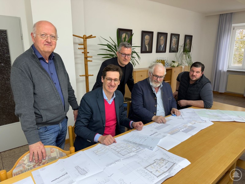 Rund 1,1 Mio. Euro fließen über die sog. Fraktionsinitiativen an insgesamt fünf Projekte im Landkreis Freyung-Grafenau, eins davon ist die Waldlaterne in Saldenburg: MdL Ebner mit Bürgermeister Max König und den Gemeinderäten Alois Weber, Dr. Stefan Hundsrucker und Markus Klessinger über den Plänen zur Sanierung der Waldlaterne. Mehrere Männer stehen und sitzen an einem Tisch mit ausgebreiteten Bauplänen und besprechen gemeinsam die geplante Sanierung eines Gebäudes.