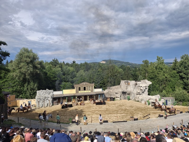 Spannende Westernshow: Pflegefamilien erlebten Action und Unterhaltung in Pullman City. Auf einer großen Freilichtbühne mit Westernkulisse verfolgen zahlreiche Besucher eine Show mit Pferden und Darstellern.