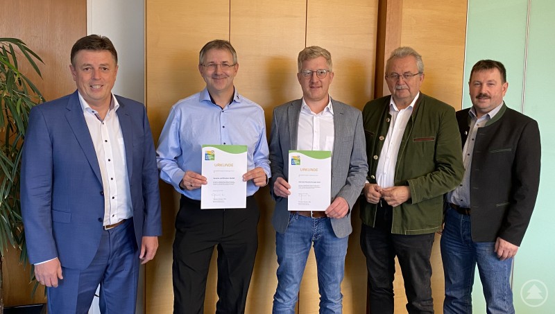 Ewald Seifert (Bürgermeister Oberschneiding), Maximilian Cerny-Probst (Bavaria certification GmbH), Reiner Obermeier (Obermeier Metalltechnologie GmbH), Landrat Josef Laumer und Hans Kienberger (Bürgermeister Konzell, von links) bei der Übergabe der Urkunde im Büro des Landrats. Fünf Männer stehen nebeneinander in einem Büro und halten Urkunden in den Händen. Zwei der Männer in der Mitte präsentieren die Auszeichnungen, während die anderen danebenstehen und in die Kamera lächeln.