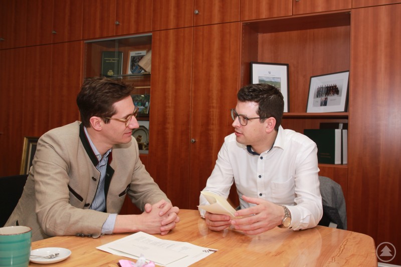 Rund 1,1 Mio. Euro fließen über die sog. Fraktionsinitiativen an fünf Projekte im Landkreis Freyung-Grafenau, eins davon ist die Aufwertung des Reinsberger Parks und des Gefühlsweg in Schönberg: MdL Dr. Stefan Ebner dazu im Gespräch mit Bürgermeister Martin Pichler. Zwei Männer sitzen sich an einem Tisch gegenüber und sprechen miteinander, während sie Unterlagen in den Händen halten.