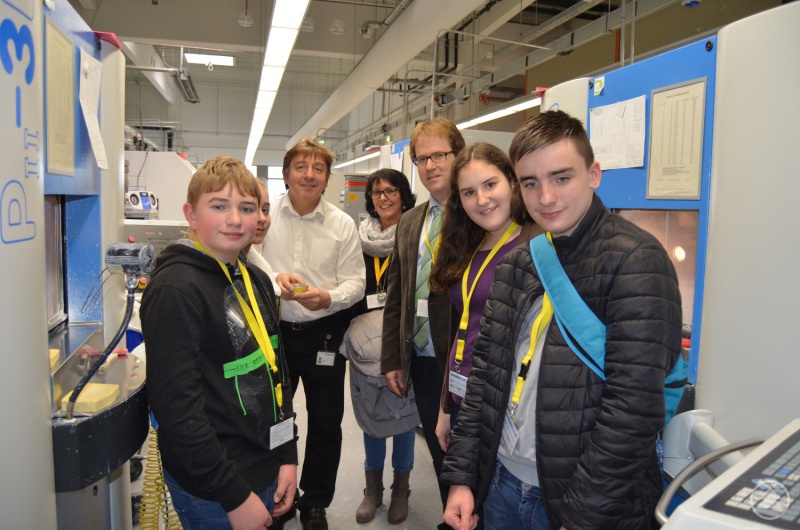 Ausbilder Anton Binder (3.v.l.) informierte Regionalmanager Stephan Lang (3.v.r.) und die Jugendlichen, wie innovative Linsen und photonische Produkte gefertigt werden.