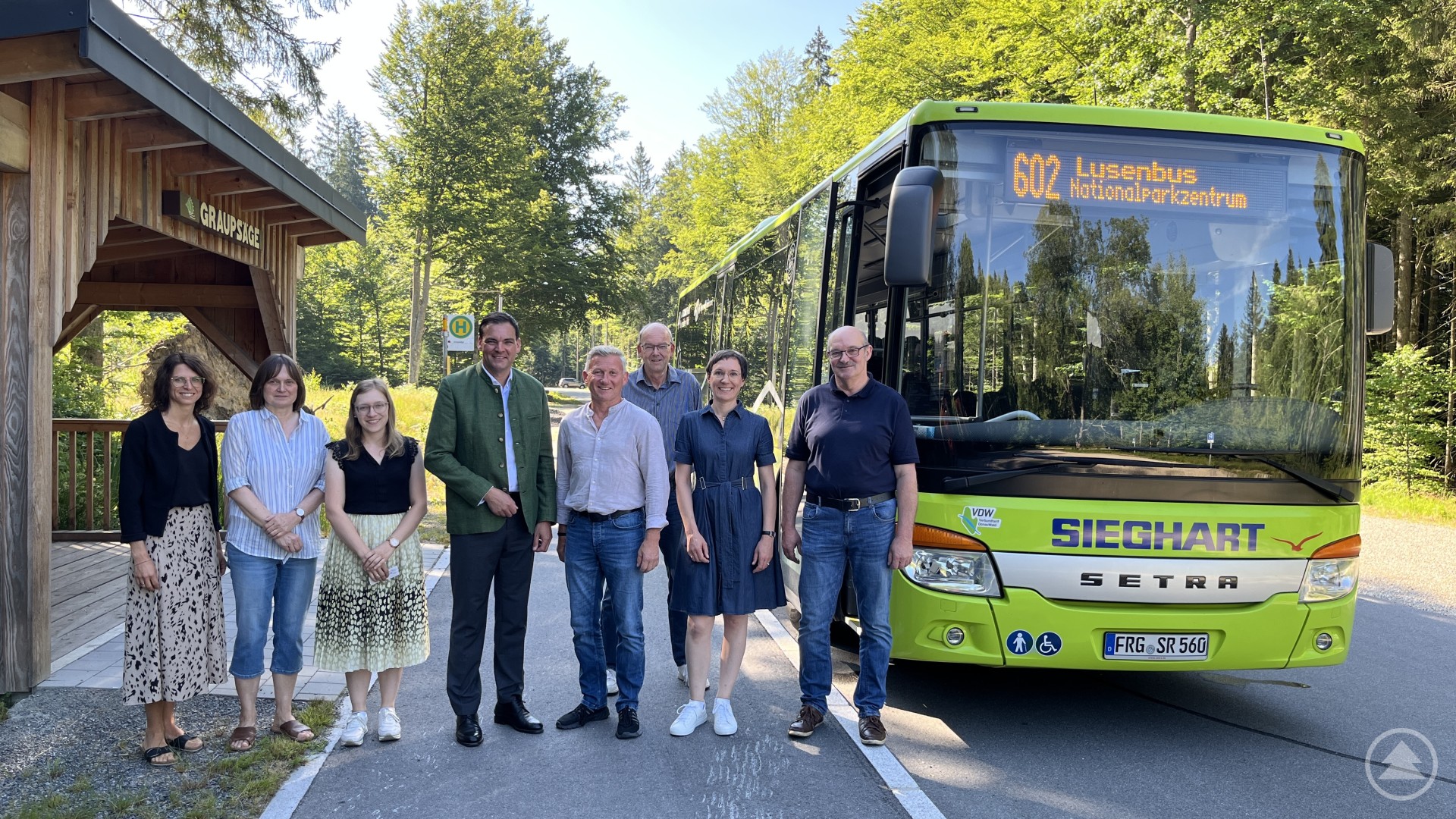 Hoffen darauf, dass das neue Verkehrskonzept rund um den Lusen von Wanderern und Nationalparkbesuchern angenommen wird (von links): Melanie Ned, Elke Ohland, Christina Schuster, Landrat Sebastian Gruber, Bürgermeister Alfons Schinabeck, Reinhard Wolf, Ursula Schuster und Herbert Maurer. Eine Gruppe von acht Personen steht auf einer Straße vor einem grünen Linienbus mit der Aufschrift „602 Lusenbus“. Der Bus gehört zum Unternehmen „Sieghart Reisen“ und befindet sich in einer waldreichen Umgebung nahe einer Holzüberdachung.