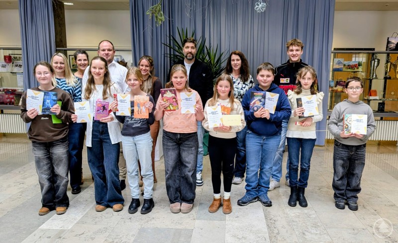 Finalisten und Jury des Vorlesewettbewerbes mit ihrer Siegerin Marie-Sophie Weber (vorne 4. von rechts). Eine große Gruppe von Schülerinnen und Schülern der sechsten Jahrgangsstufe steht gemeinsam mit Mitgliedern der Jury im Medienraum der Realschule Grafenau. Die Kinder halten Urkunden und Bücher in den Händen und lächeln in die Kamera.