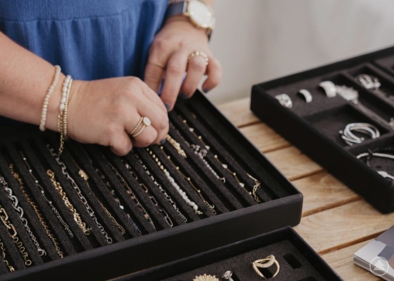 Nahaufnahme verschiedener Schmuckst&uuml;cke in Silber und Goldt&ouml;nen die auf blauen Samt L&auml;den pr&auml;sentiert werden.