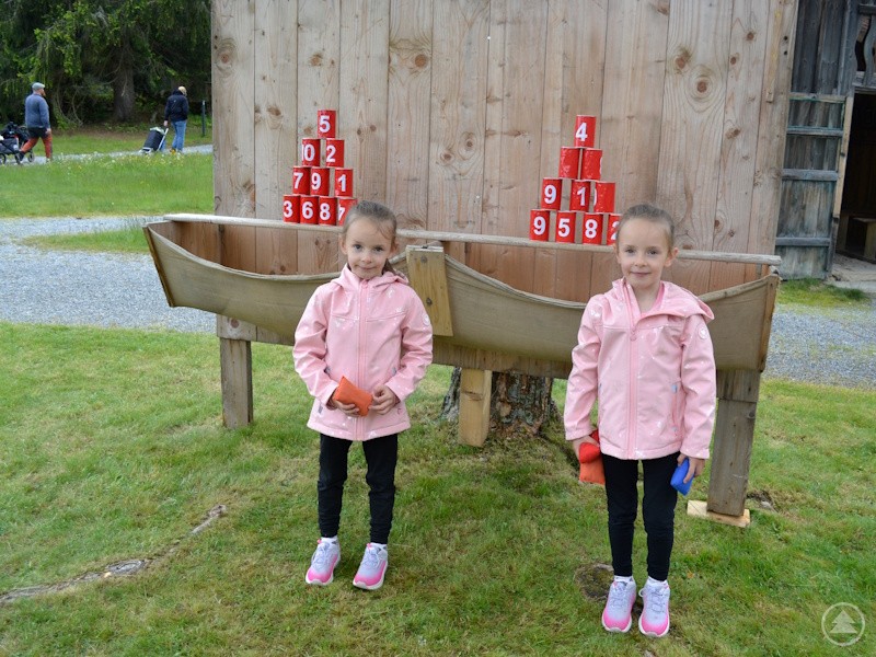 In den Regenpausen gern genutzt: Dosenwerfen gehörte zu den beliebtesten Spielstationen. Zwei kleine Mädchen in rosa Jacken stehen mit Wurfsäckchen vor einer Dosenwurfstation.