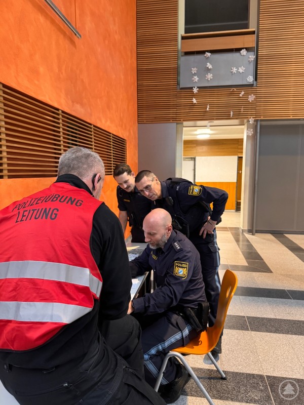 Mehrere Polizisten und ein &Uuml;bungsleiter mit roter Weste mit der Aufschrift 