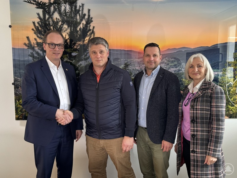 MdL Martin Behringer (links) überbringt die Förderzusage für das Glück-auf-Stadion in Bodenmais an 2. Bürgermeister Jochen Koller, TSV-Vorsitzenden Robert Stiefel und eine Vertreterin der Gemeinde. Vier Personen stehen nebeneinander in einem Raum und schütteln sich die Hände, während sie gemeinsam über die geplante Förderung für die Sanierung des Glück-auf-Stadions sprechen.