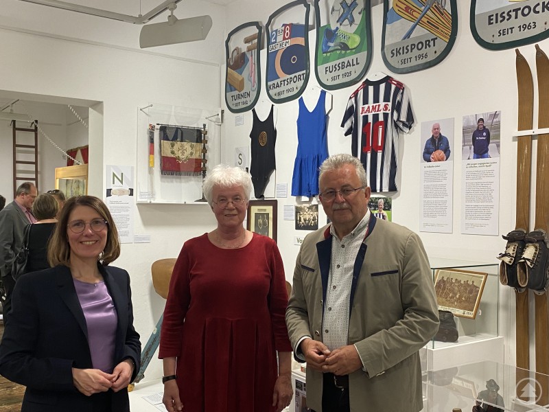 Bürgermeisterin Andrea Probst, Museumsleiterin Barbara Michal und Landrat Josef Laumer (v.l.) bei der Eröffnung der Sonderausstellung im Kreismuseum auf dem Bogenberg. Drei Personen – Bürgermeisterin, Museumsleiterin und Landrat – stehen im Ausstellungsraum des Kreismuseums Bogenberg vor Exponaten zur Vereinskultur.