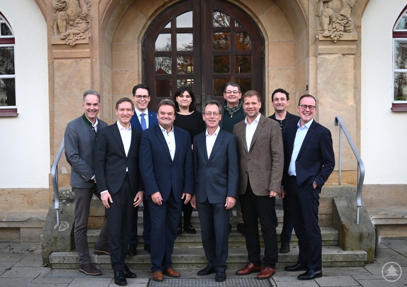 Bei der Vorstands- und Beiratssitzung des Niederbayern-Forums wurden auch ehemalige Mitglieder des Gremiums verabschiedet: Peter Schmid (Mitte links) und Professor Dr. Fritz Pörnbacher (Mitte rechts). Im Bild von links nach rechts: Vorstandsmitglied Alexander Schreiner (Hauptgeschäftsführer IHK Niederbayern), Regierungspräsident Rainer Haselbeck (2. Vorsitzender Niederbayern-Forum), Beiratsmitglied Dr. Christian Moser (Oberbürgermeister Stadt Deggendorf), Beiratsmitglied Manuela Königbauer (Regierung von Niederbayern), Bezirkstagspräsident Dr. Olaf Heinrich (1. Vorsitzender Niederbayern-Forum), Beiratsmitglied Rudi Fellner (Präsident BBA), Alexander Zendelbach (Geschäftsstelle), Dr. Reinhard Saller (Geschäftsführer Niederbayern-Forum). Eine Gruppe von neun Personen steht vor dem Eingang eines historischen Gebäudes. Die Teilnehmenden der Vorstands- und Beiratssitzung posieren gemeinsam auf den Treppenstufen für ein Gruppenfoto.