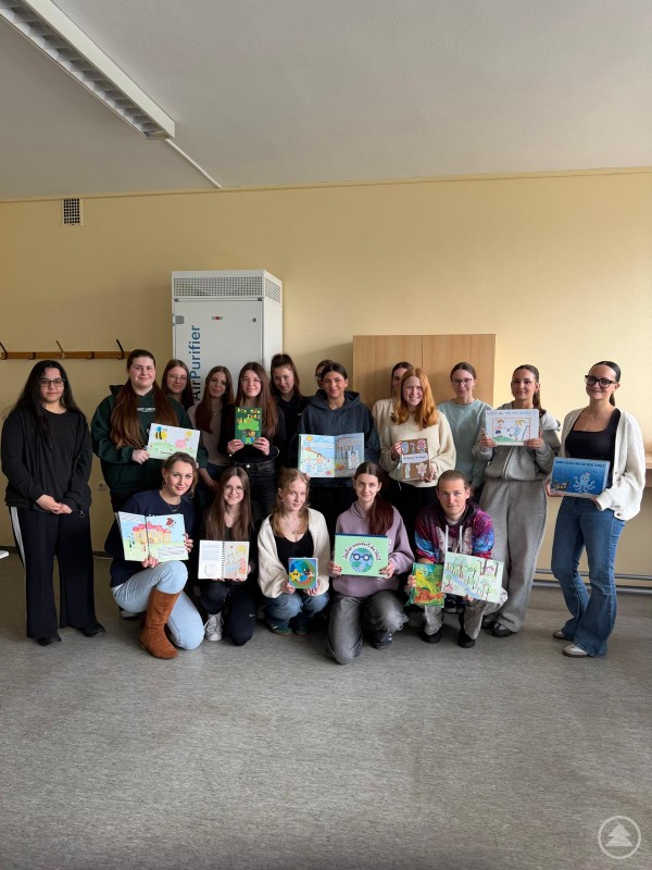 Gruppenfoto der Schülerinnen und Schüler der FOS BOS Deggendorf mit ihren selbst gestalteten Bilderbüchern Eine Gruppe von Schülerinnen und Schülern steht und kniet in einem Klassenzimmer und präsentiert selbst gestaltete Bilderbücher, die sie in den Händen halten.