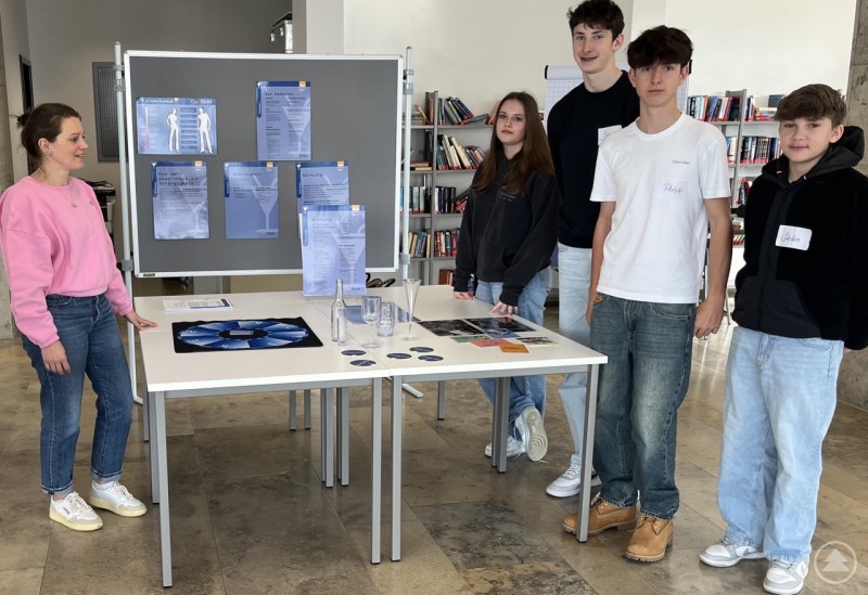 Schülerinnen und Schüler der Jahrgangsstufe 8 zusammen mit Frau Johanna Dorner und Herrn Christopher Kessel vom Gesundheitsamt Freyung-Grafenau Schülerinnen und Schüler stehen gemeinsam mit einer Betreuerin an einem Infostand