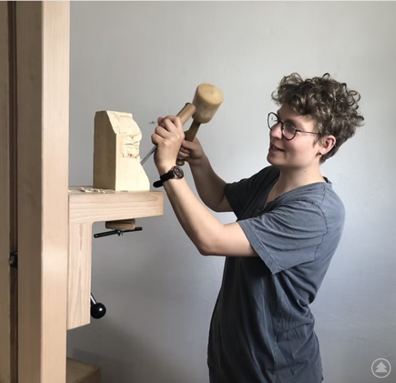Die junge Holzbildhauerin Kathrin Ringlstetter bei der Arbeit an einer ihrer Skulpturen. Kathrin Ringlstetter arbeitet mit Hammer und Meißel an einer Holzskulptur.